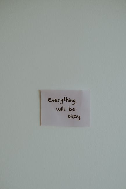 A simple note stating 'everything will be okay' on a blank wall, conveying optimism and simplicity.