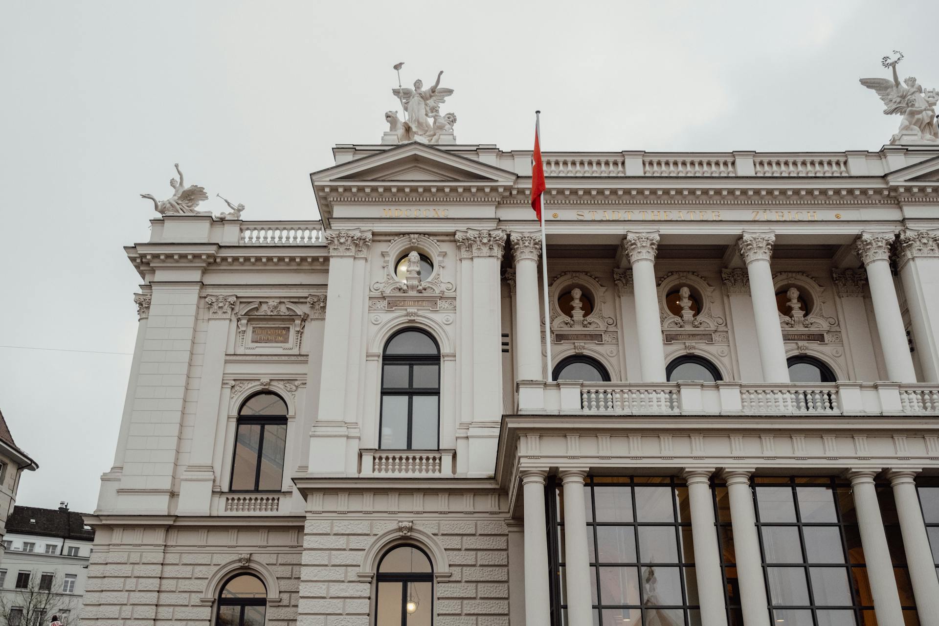 A low angle view of the majestic Zurich Opera House exterior with a cloudy sky backdrop.