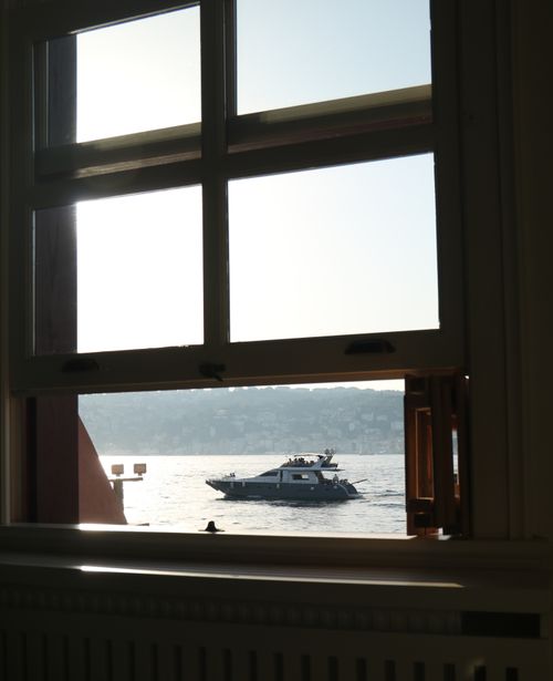 Free Yacht seen from indoors through a window with scenic harbor view at sunset. Stock Photo