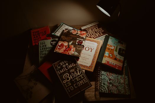 A collection of books illuminated under a lamp, creating a warm and inviting reading space.