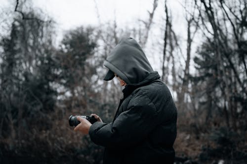 Side View of a Man Taking Pictures with a Camera in the Forest 
