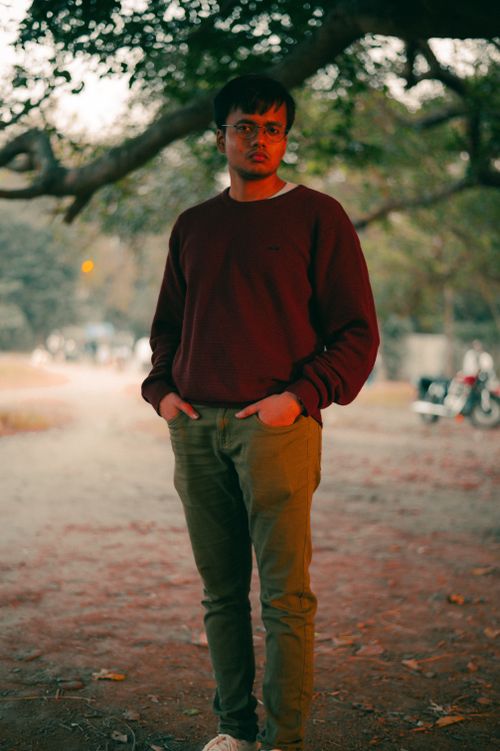 Free Portrait of a man in a red sweater standing outdoors in a park during fall. Stock Photo