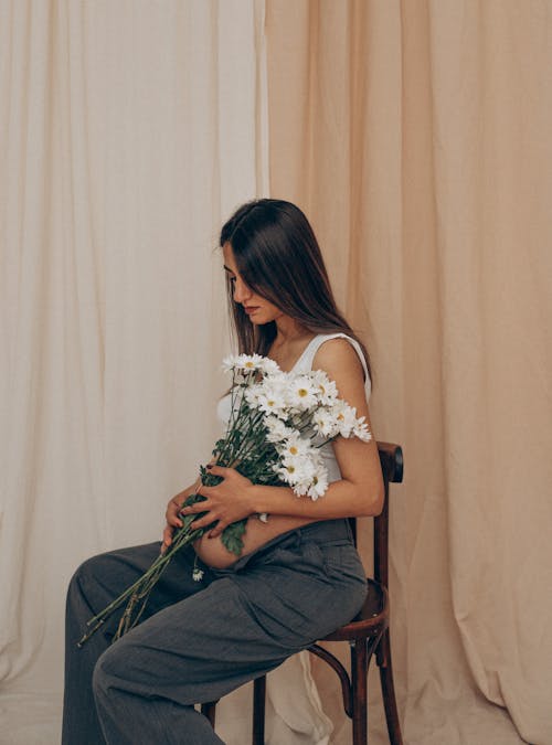 Brunette Woman Sitting with Flowers on Chair
