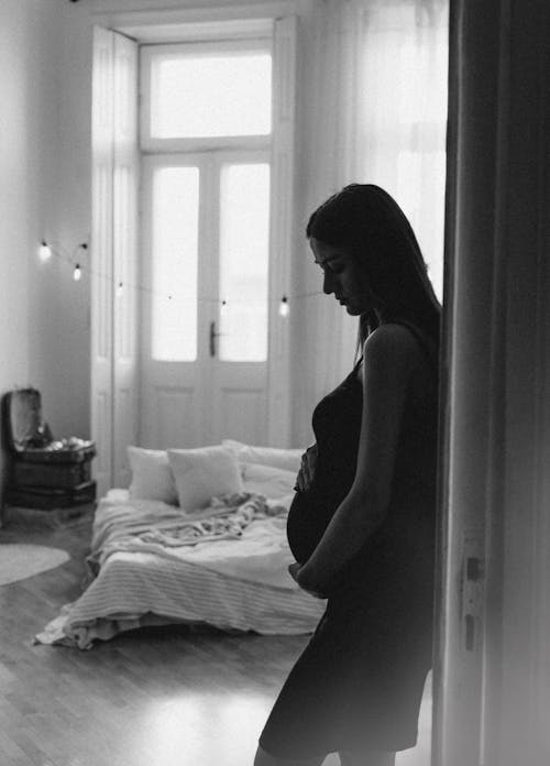 Pregnant Woman Standing in the Doorway of her Bedroom 