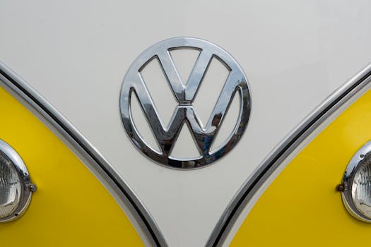 Detailed view of the Volkswagen emblem on a vintage yellow and white van, showcasing classic design.