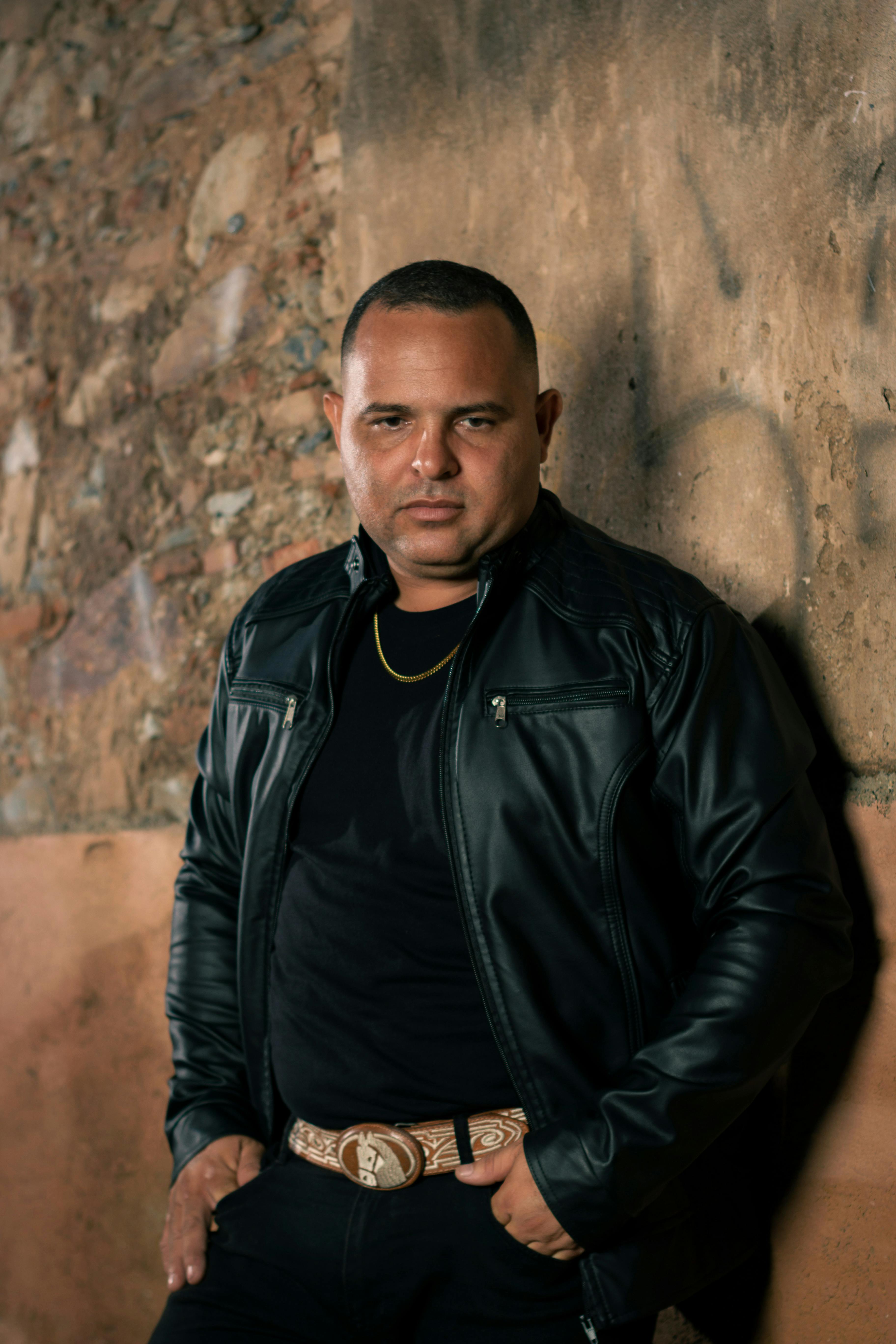 Man with leather jacket standing against a rustic wall in Guama, Venezuela.