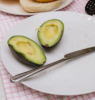 Fresh avocado halves on a plate with a knife, perfect for healthy meals and recipes.