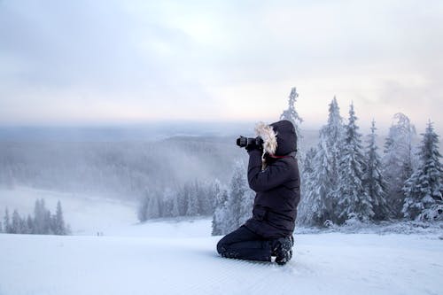 Side View of a Person Photographing Snowy Mountain Landscapes