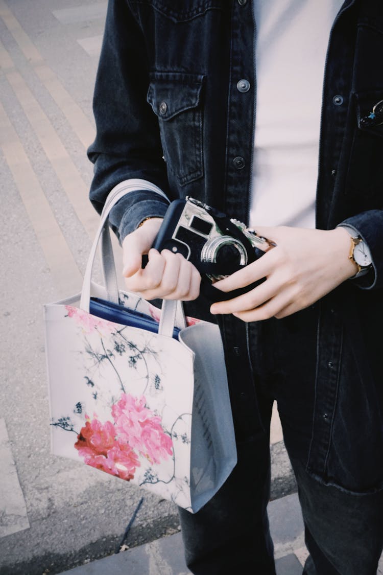 Close-up Of A Person Holding A Vintage Camera And A Gift Bag 