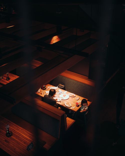 Free A father and daughter enjoy a quiet dinner in a warmly lit restaurant booth, capturing a moment of family togetherness. Stock Photo