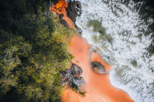 Free Stunning aerial view of a colorful beach with lush greenery and crashing waves in Chukai, Malaysia. Stock Photo