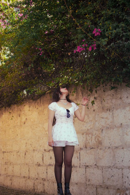 Model in White Summer Mini Dress Looking at the Flowers