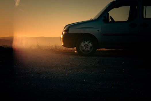 Side view of a first-generation Fiat Doblò minivan at sunrise on a rural road.