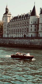 A boat sailing the Seine River with the historic Conciergerie in the background, Paris.