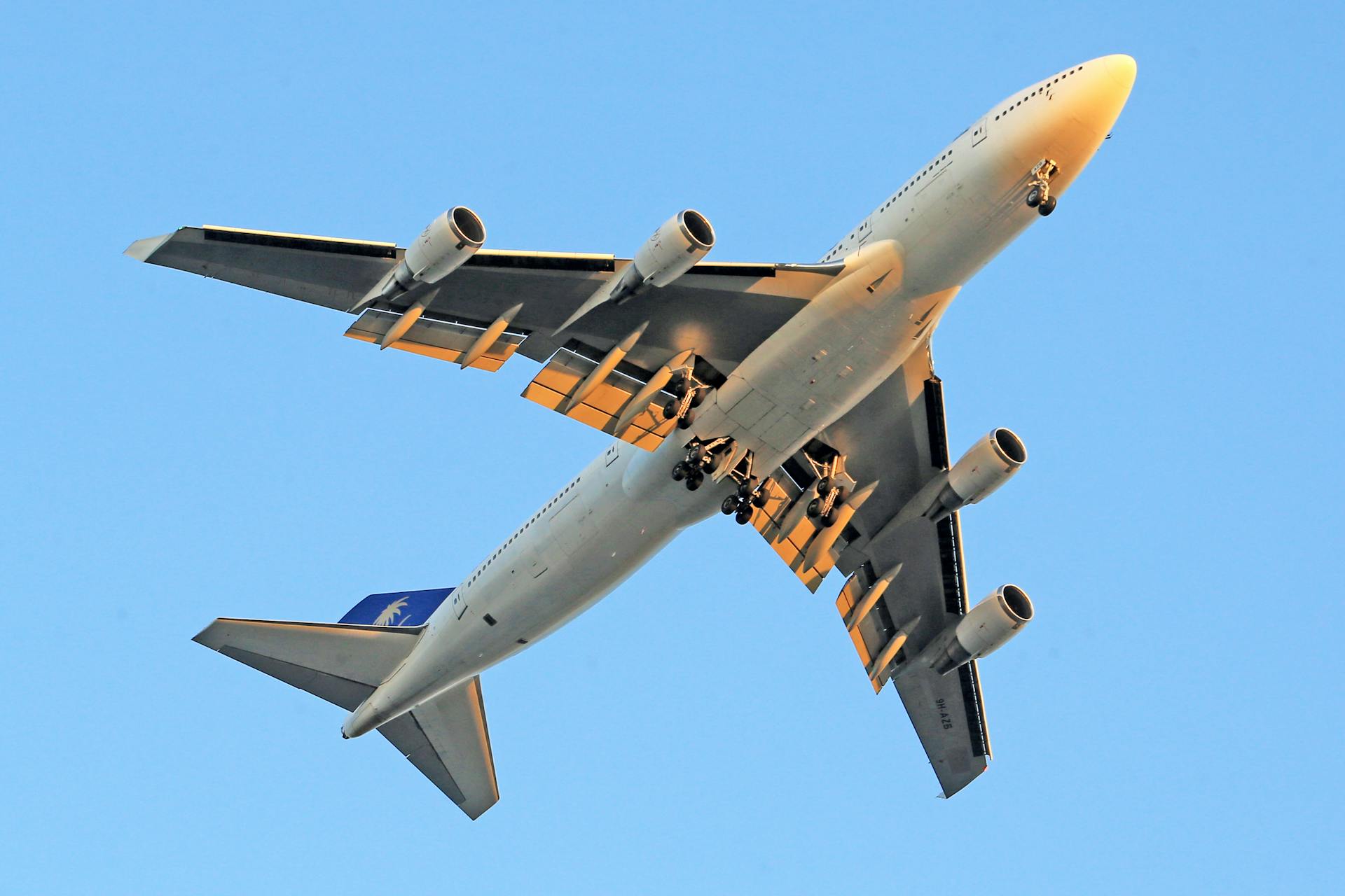 A Boeing 747 aircraft photographed mid-flight against a clear blue sky.