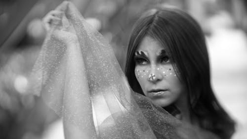 Free Portrait of a Pretty Brunette Wearing Face Paint Holding a Translucent Veil Stock Photo