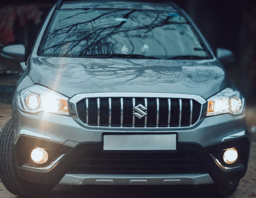 Close-up of the front view of a silver Suzuki SX4 S-Cross SUV highlighting its grill and headlights.