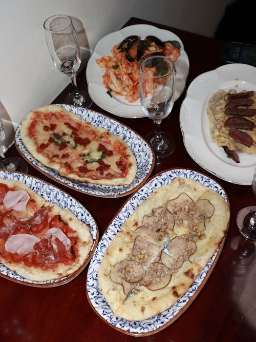 Table with Homemade Pizzas on Patterned Plates