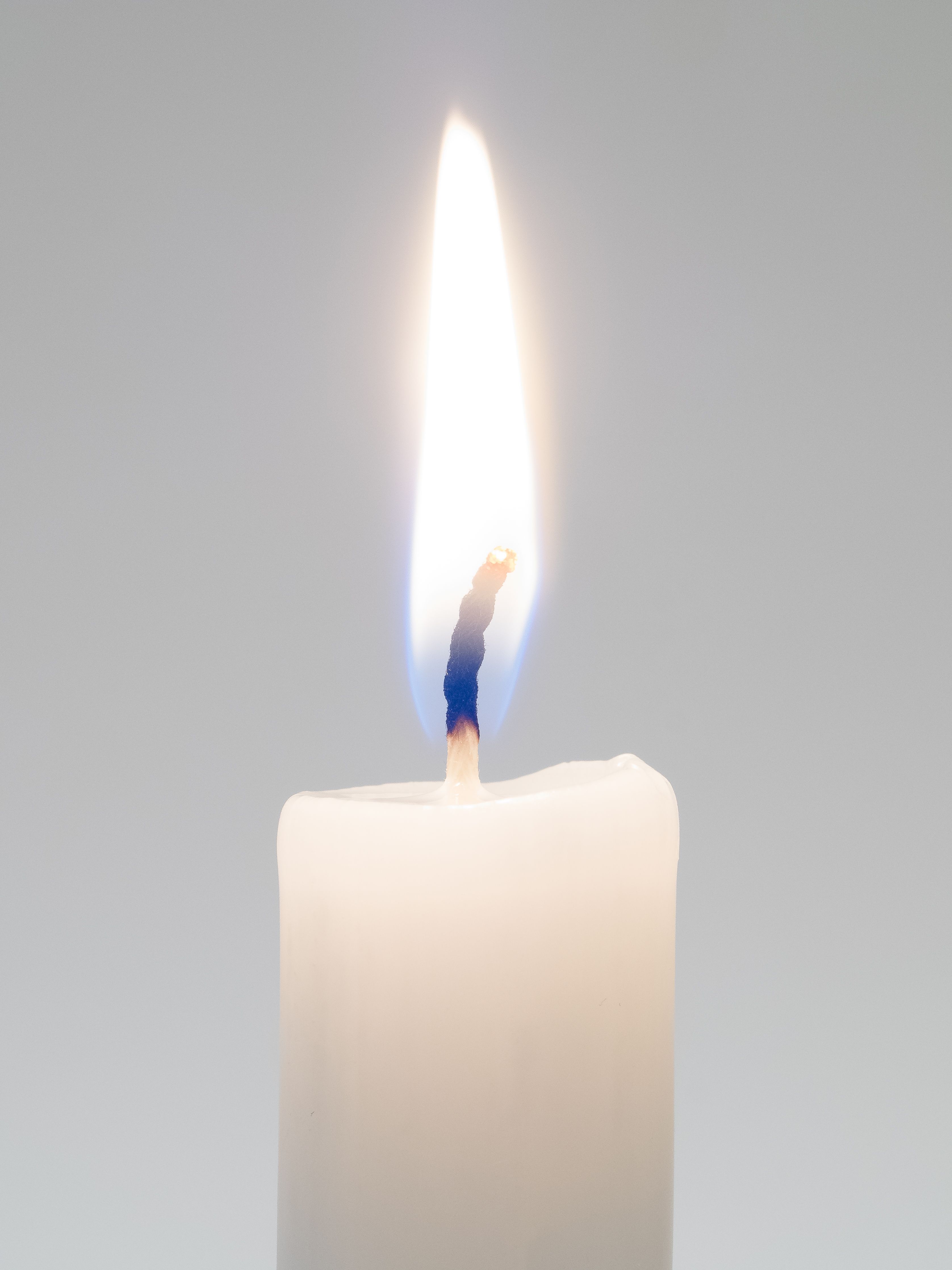 A detailed view of a candle with a bright flame, perfect for themes of warmth, light, and serenity.