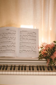A serene setting with sheet music open on a white piano, complemented by soft lighting and a floral arrangement.
