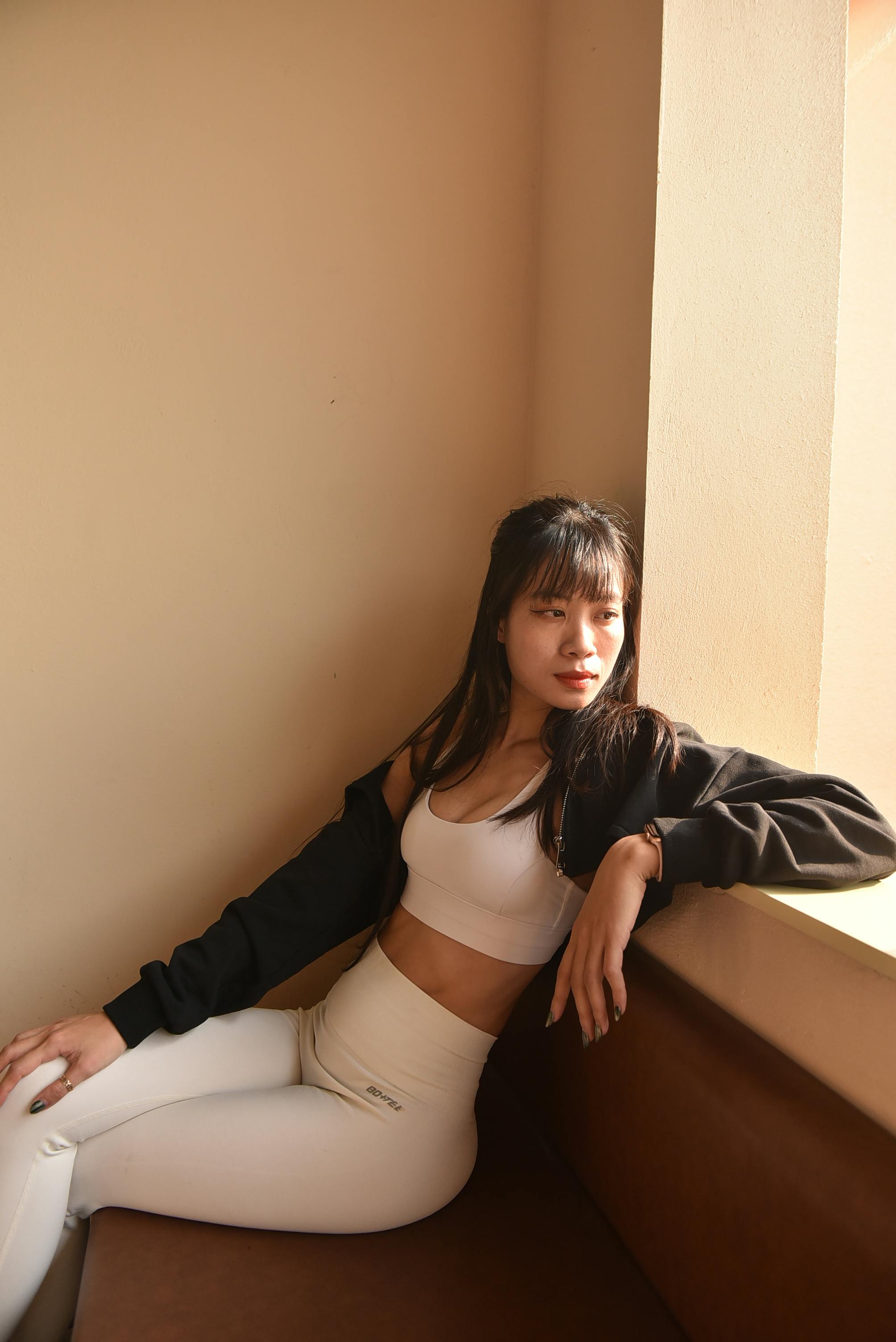 Fashionable woman in casual wear relaxing indoors by the window in natural light.
