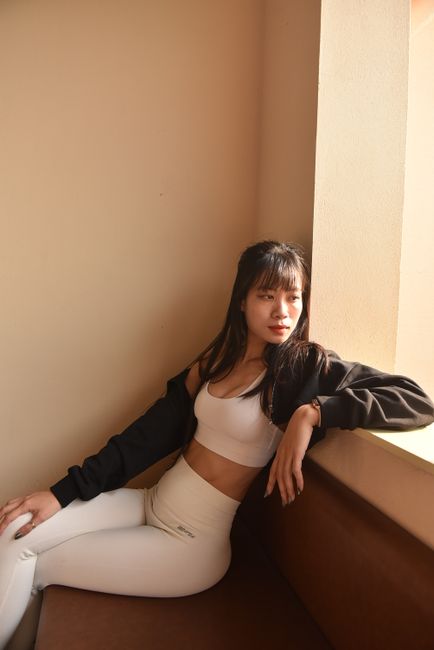 Fashionable woman in casual wear relaxing indoors by the window in natural light.