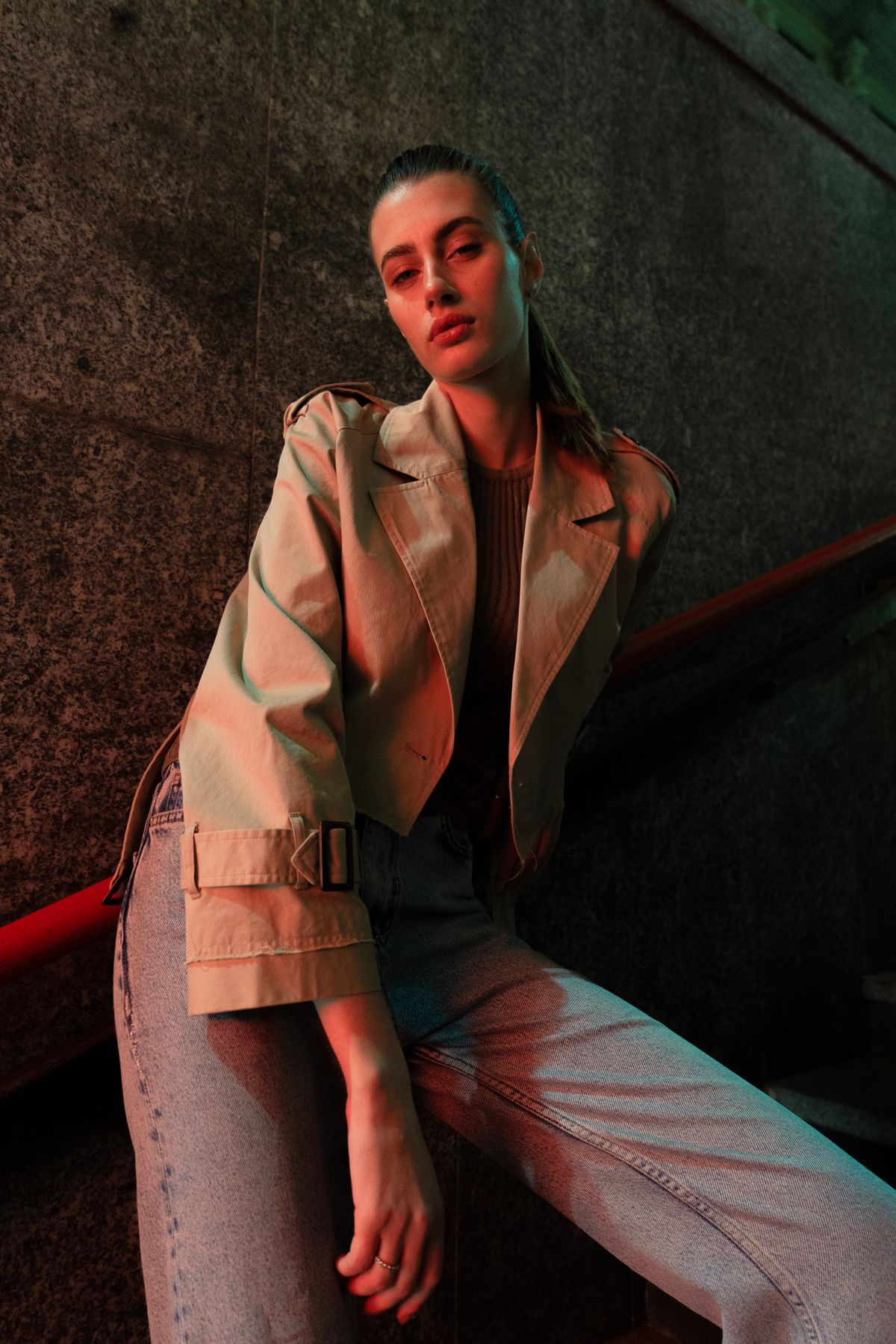 A model in a coat posing outdoors at dusk — the runway trench