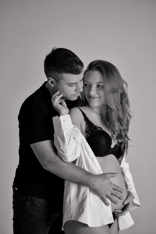 Free A serene black and white portrait of a loving couple embracing during pregnancy. Stock Photo