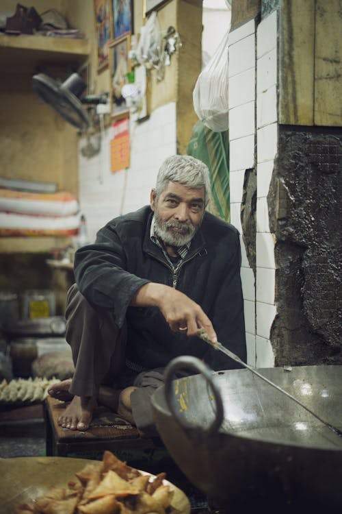 Portrait of a Senior Man Sitting in Front of a Large Wok