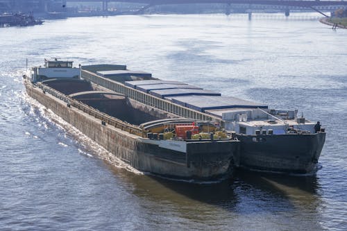 Two Cargo Ships Sailing Along the River