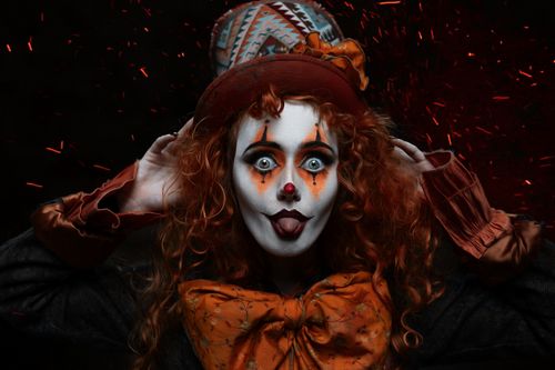 Free Colorful clown with stage makeup and top hat, playfully posing with a dramatic expression. Stock Photo