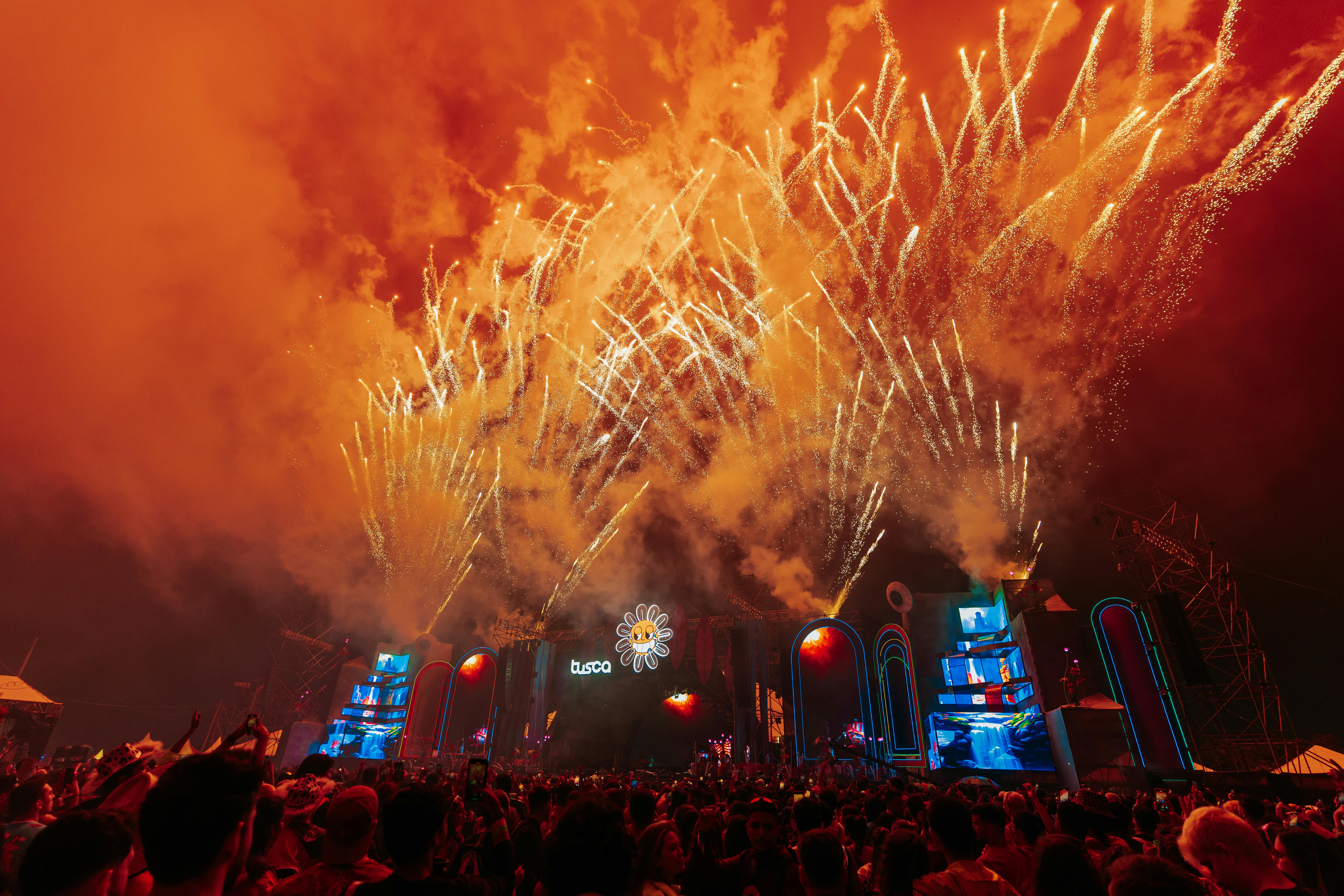 A breathtaking fireworks show over a lively concert crowd in São Carlos, Brazil, at night.