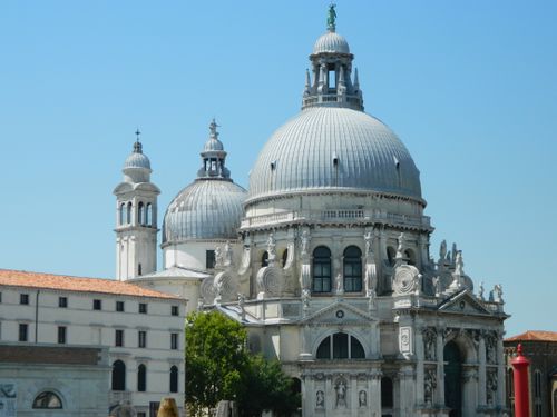 Explore the stunning architecture of Venice's iconic basilica with majestic domes under a bright blue sky.