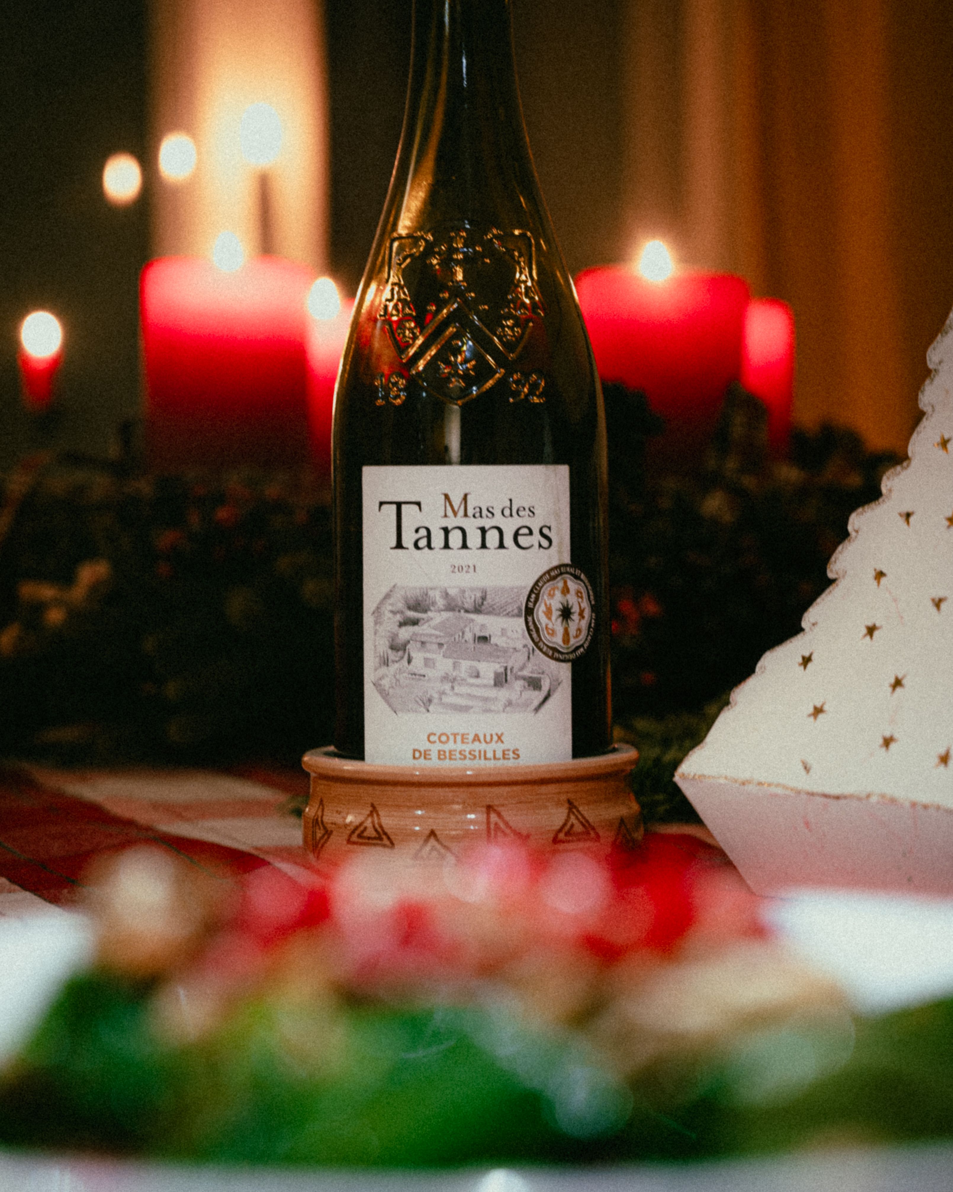 A beautifully crafted wine bottle with red candles, creating a warm, festive atmosphere perfect for celebrations.