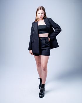 Fashion model posing confidently in a stylish black blazer and shorts against a white background.
