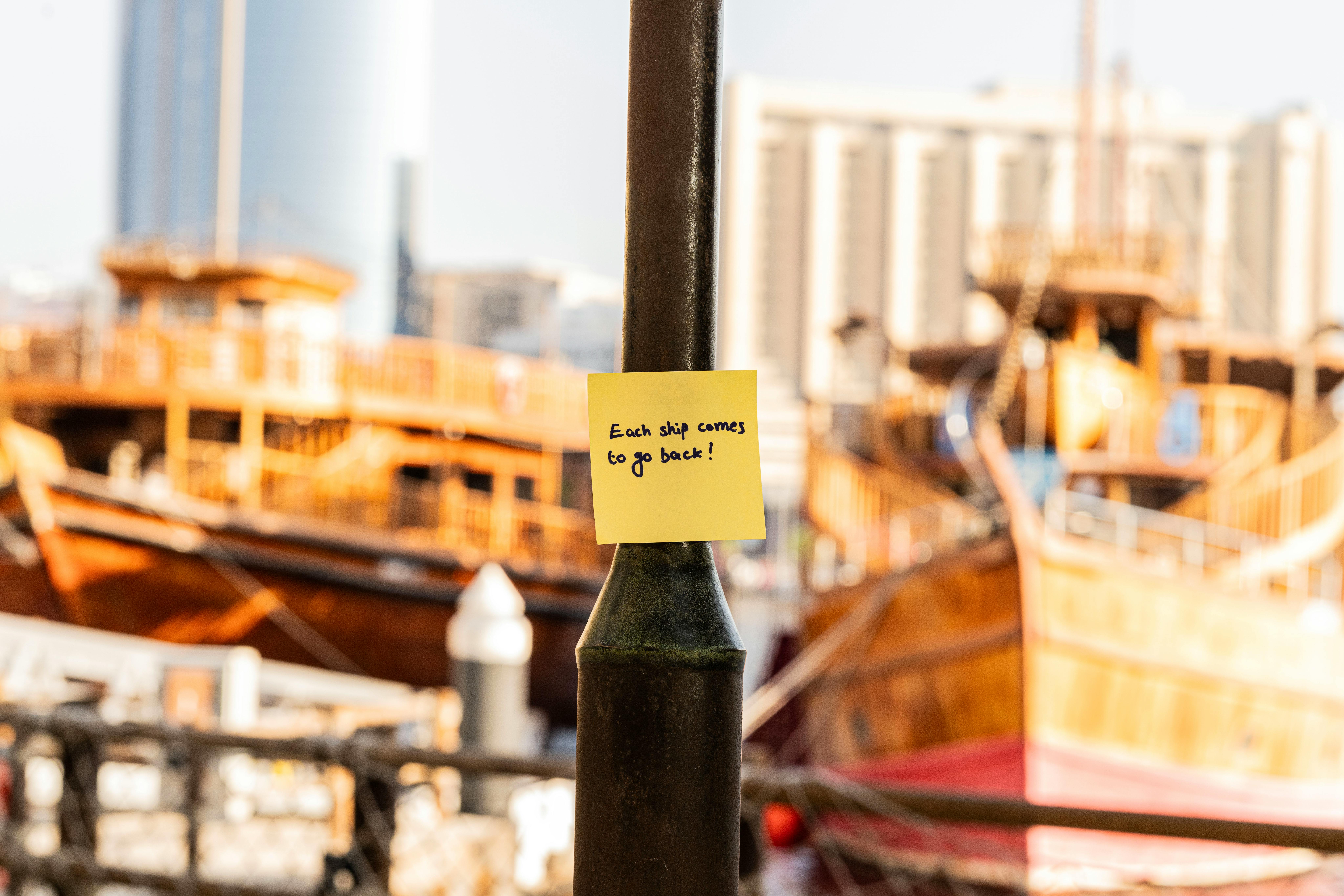 Yellow sticky note with motivational phrase against a backdrop of Dubai Marina's traditional boats.