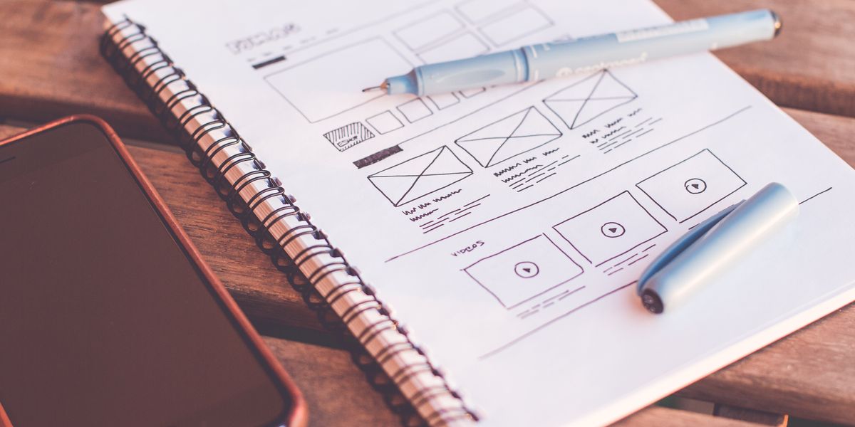 UX designer sketching wireframes and user flows on whiteboard with colorful markers showing design process