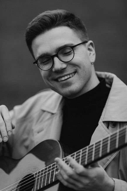 Black and white portrait of a smiling musician with a guitar.