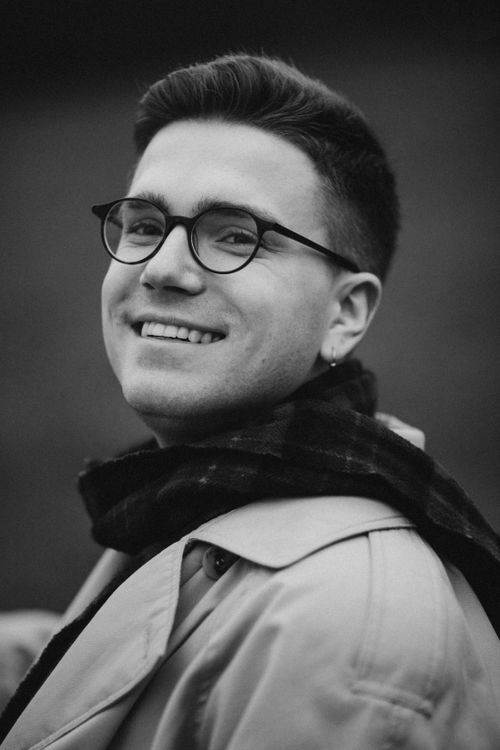 Free Stylish black and white portrait of a young man smiling with eyeglasses and a scarf. Stock Photo