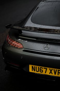 Sleek Mercedes AMG car with raindrops, parked in a London street. Modern automotive design captured in moody lighting.