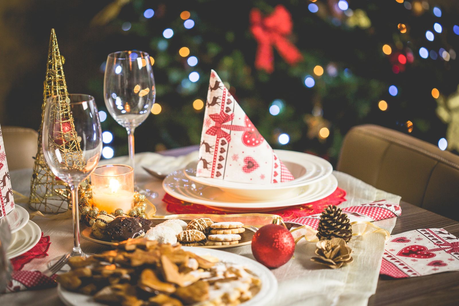 Beautifully set Christmas table with decorations, food, and drinks under festive lights - diy christmas centerpiece ideas