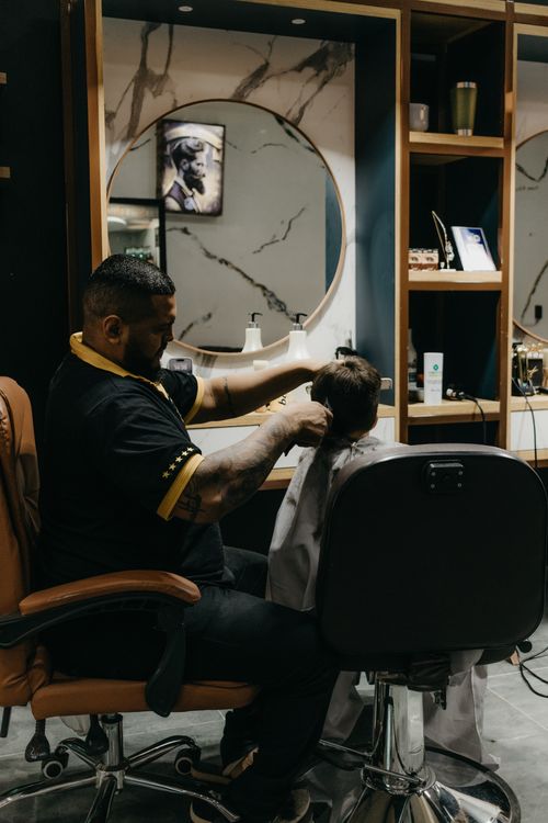 Free A barber skillfully cuts a child's hair in a modern salon setting, offering comfort and professional service. Stock Photo