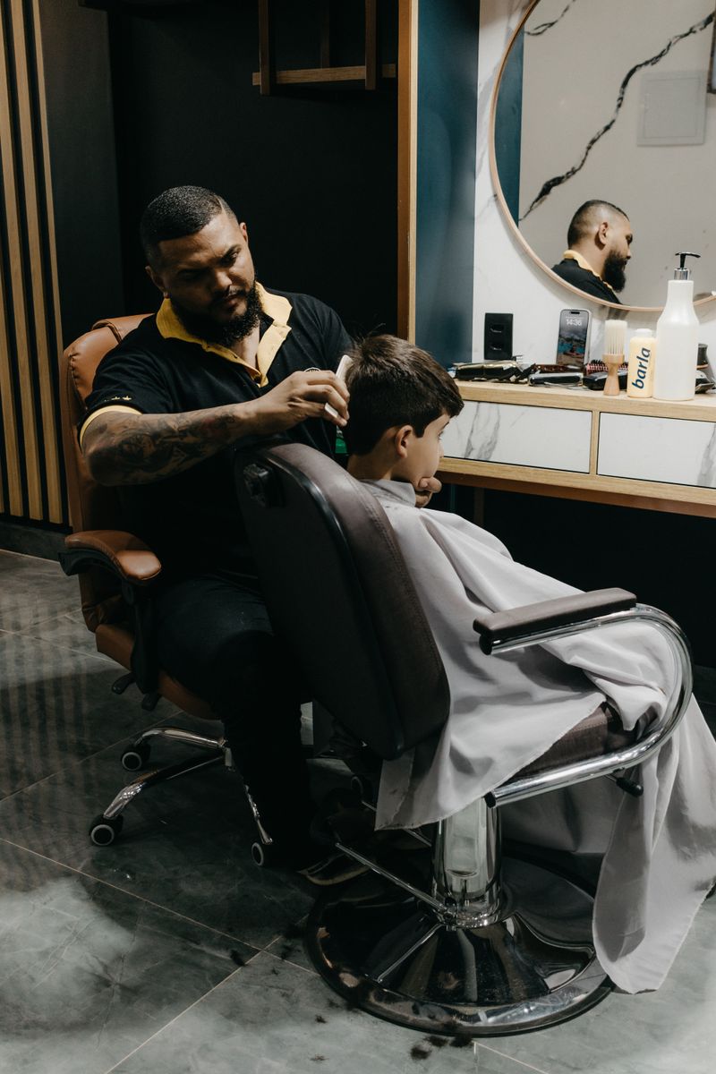 Barbeiro realizando corte de cabelo em um menino