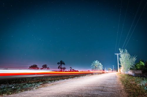 Free Long exposure of car lights on a rural road under a starry night sky. Stock Photo