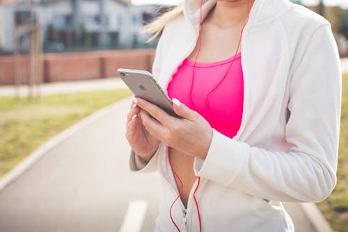 Woman in White Jacket Holding Silver Iphone