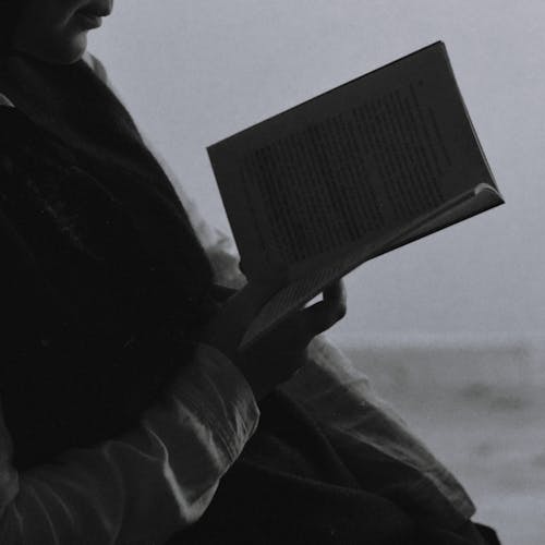 Black and White Photography of a Woman Reading a Book