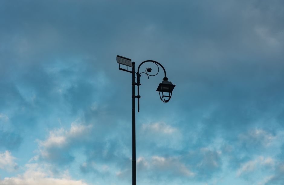 A street lamp with an integrated solar panel against a dramatic sky — the kind of supplier-side product a working solar contractor also handles.