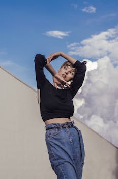 一位时尚女士在充满活力的多云天空背景下，穿着牛仔裤摆出姿势