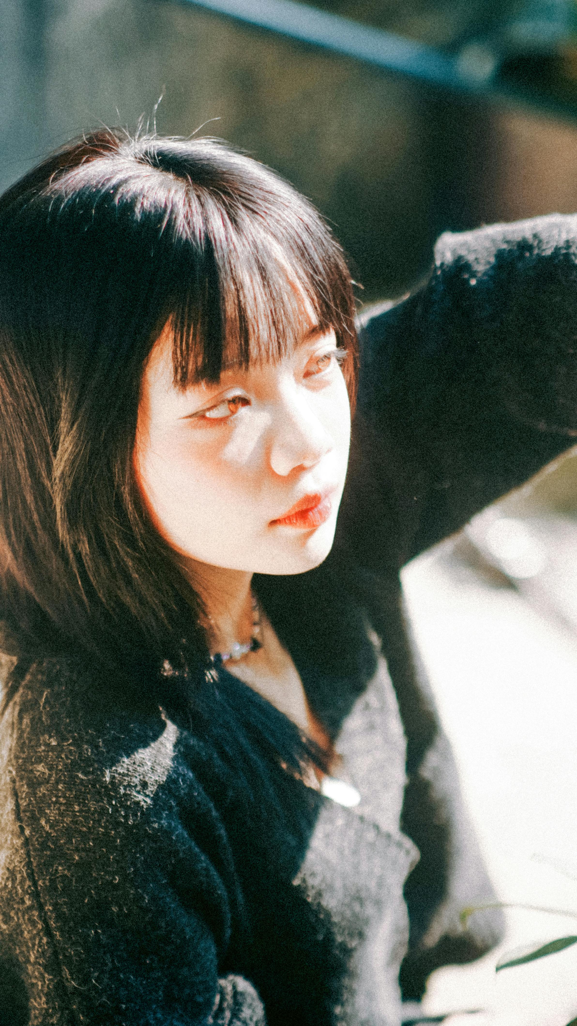 A young woman dressed in a cozy sweater enjoys the warm sunlight on an autumn day.