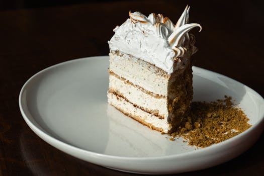 A beautifully presented slice of layered cake with cream frosting on a white plate.